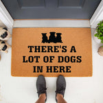 Pug dog welcome doormat featuring three black pug silhouettes and the text There is a lot of dogs in here, this natural coir fiber outdoor floor mat is a funny pet lover front porch decor piece for any dog owner home entrance.
