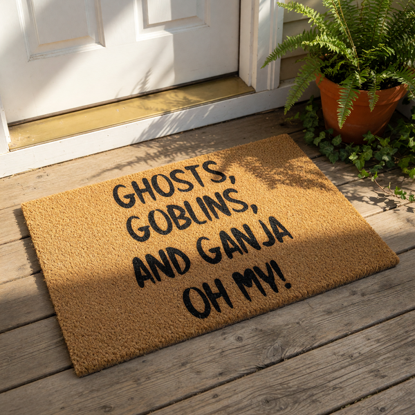 Funny Halloween doormat featuring the text Ghosts, Goblins, and Ganja Oh My printed in black on a natural coir fiber welcome mat, perfect for a spooky front porch entry or a humorous home decor statement for cannabis enthusiasts.