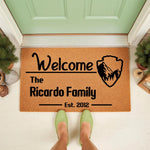 Personalized family name doormat featuring a mountain landscape emblem, this custom coir welcome mat for front porch decor displays a family name and established year on a durable natural fiber rug for a stylish home entrance.