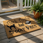 Spooky Halloween doormat featuring a black cat, bat, and moon design with the text Thick Thighs And Spooky Vibes, this natural coir welcome mat is a funny front porch rug for fall home decor and seasonal entryway floor mats.