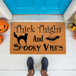 Funny Halloween doormat with black cat and bat design on a natural coir welcome mat, featuring the text Thick Thighs And Spooky Vibes for a festive fall porch decor look that adds humor to your front door entrance this autumn
