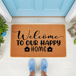 Welcome to our happy home doormat featuring black script and block lettering on a natural coir fiber mat, placed on a front porch in front of a blue door, making a stylish housewarming entrance rug for your home decor and