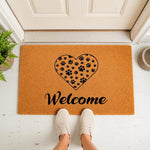 Paw print heart welcome doormat for pet lovers, featuring a natural coir fiber texture with a black heart design filled with animal paw prints, placed on a front porch entryway for a stylish and inviting home decor look.