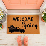 Welcome Spring doormat featuring a black truck graphic on natural coir fiber, perfect for seasonal porch decor.