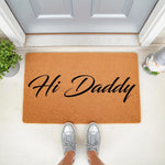 Hi Daddy doormat for front porch, a natural fiber coir welcome mat with black script text, placed at a front door entrance with a person wearing silver sneakers standing on it, creating a fun and personalized home entryway decor