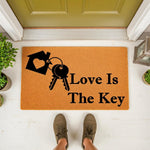 Love Is The Key doormat, a natural fiber welcome mat for front porch decor featuring a house and key graphic, perfect for new home housewarming entryways or as a stylish outdoor floor rug for your home entrance and front door