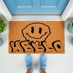Melting smiley face hello doormat featuring a groovy retro design on natural coir fiber, perfect as a fun front porch welcome mat for your home entrance, shown on a porch with blue sneakers standing on the rug for a stylish look.