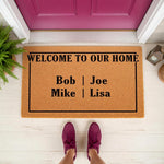 Personalized family name welcome doormat featuring a natural coir fiber texture and black text that reads Welcome To Our Home, displayed on a front porch with a bright pink door and a person wearing purple sneakers standing on