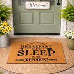 Funny kitchen doormat with text reading If You Want Breakfast In Bed Sleep In The Kitchen, featuring a natural coir fiber welcome mat on a round rug outside a front door, perfect for home decor, housewarming, or a humorous