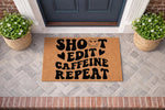 Shoot Edit Caffeine Repeat doormat for photographers, a natural coir welcome mat with bold black typography and a smiley face icon, placed on a front porch entryway to create a stylish and functional home decor entrance for