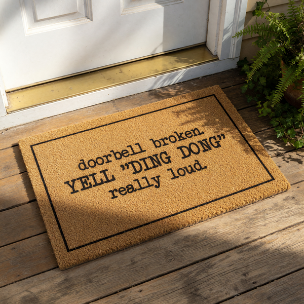 Funny doorbell broken doormat with a natural coir texture and black border, featuring the text YELL DING DONG really loud for a humorous front porch welcome mat that serves as a quirky housewarming decor piece for your home