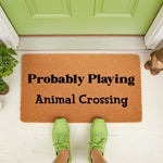 Funny gaming doormat with text reading Probably Playing Animal Crossing, featuring a natural coir fiber welcome mat placed on a porch, perfect for video game fans looking for a unique front door rug or housewarming entryway decor.