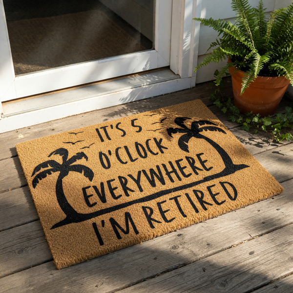 Tropical retirement doormat with palm tree design and funny quote, this natural coir welcome mat features black text reading It's 5 O'Clock Everywhere I'm Retired, perfect for a front porch entry or a fun housewarming decor gift.