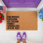 4th of July coir doormat featuring patriotic holiday text on a natural fiber welcome mat, displayed on a front porch with a purple door, American flag, and blue flowers for a festive summer home decor entrance and outdoor floor