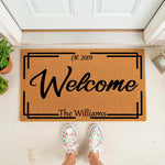 Personalized family name welcome doormat with a modern border design, featuring custom established year text on a natural coir fiber mat, perfect for a front porch entryway or housewarming gift for a new home or wedding couple.