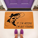 Fishing themed welcome doormat with a black fish graphic and text reading If I am missing I am out fishing, placed on a porch in front of a purple door, perfect for outdoor home decor or a funny housewarming entry rug for anglers.