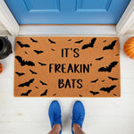 It's Freakin' Bats Halloween doormat featuring a natural coir fiber texture with black bat silhouettes, perfect for a spooky front porch welcome mat decor during the fall season for any home entryway or outdoor house entrance.