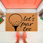 Golf themed welcome doormat with a printed golf ball and tee design featuring the text let's par tee, this natural fiber coir outdoor floor mat is placed on a porch in front of a coral door for a fun sports home entrance decor