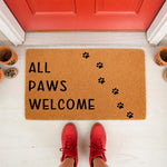 All Paws Welcome doormat for pet lovers, a natural fiber welcome mat with black paw prints placed on a porch in front of a red door, perfect for dog owners or cat lovers looking for a cute, durable outdoor rug for their home