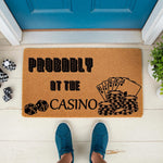 Probably At The Casino doormat featuring poker cards, chips, and dice graphics on natural coir fiber, a funny welcome mat for gamblers and card game lovers placed on a front porch entryway for a unique home decor look.