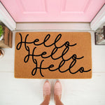 Hello Hello Hello doormat featuring natural coir fiber material with black script lettering, placed on a porch in front of a pink door as a stylish welcome mat for home entryway decor and front door floor mat housewarming needs.