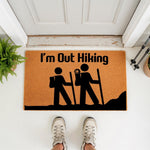 Hiking themed doormat with I am Out Hiking text and stick figure backpackers, this natural coir welcome mat is a funny outdoor front porch rug for hikers, nature lovers, and camping enthusiasts who enjoy mountain trail adventures.