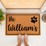Personalized family name coir doormat with a paw print design, featuring a natural fiber welcome mat for front porch decor, custom last name floor rug for pet lovers, and a durable outdoor entrance mat for a home entryway.