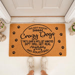 Funny dog doormat with paw prints and text warning about crazy dogs and no soliciting, placed on a porch floor.