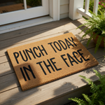 Punch Today In The Face funny doormat featuring bold black text on a natural coir fiber welcome mat, perfect for a front porch entry or apartment door decor that adds a humorous and motivational touch to your home entrance.