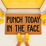Punch Today In The Face funny doormat featuring bold black text on a natural coir welcome mat, placed at a bright yellow front door with yellow boxing gloves and matching yellow sneakers for a motivational home entryway decor