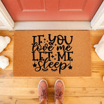 Funny sleep quote doormat with black text on a natural coir fiber welcome mat, featuring a humorous message for bedroom decor or front porch entryways, placed on a wood floor with a person wearing pink sneakers standing in front