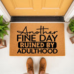 Funny Another Fine Day Ruined By Adulthood doormat, a natural coir fiber welcome mat with black text for a front porch entry, featuring a humorous quote design that makes a sarcastic housewarming decor piece for any home entrance.