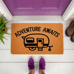 Adventure Awaits camper doormat featuring a travel trailer design on a natural coir welcome mat, perfect for outdoor porch decor, camping enthusiasts, and home entryways with a fun, rustic, and adventurous outdoor living theme.