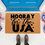 Hooray for the USA doormat featuring patriotic stars and bold black text on a natural coir welcome mat, perfect for a front porch entry way during summer holidays or Independence Day celebrations with festive red white and blue