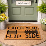 Funny kitchen doormat with spatula graphic and Catch You On The Flip Side text, a natural coir fiber welcome mat for front porch decor that makes a humorous housewarming gift for home cooks and grill masters who love cooking.