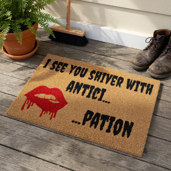Rocky Horror Picture Show doormat featuring a natural coir texture with black text that reads I see you shiver with antici...pation and a bold red graphic of dripping lips, perfect for a spooky or movie-themed front porch