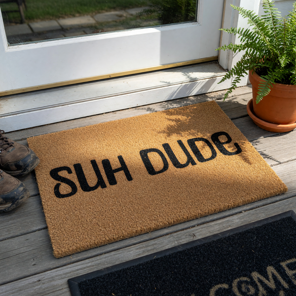 Suh Dude coir doormat featuring a natural brown fiber texture and bold black lettering centered on the front, providing a humorous and casual welcome for guests at your front door entrance on a clean white studio background.