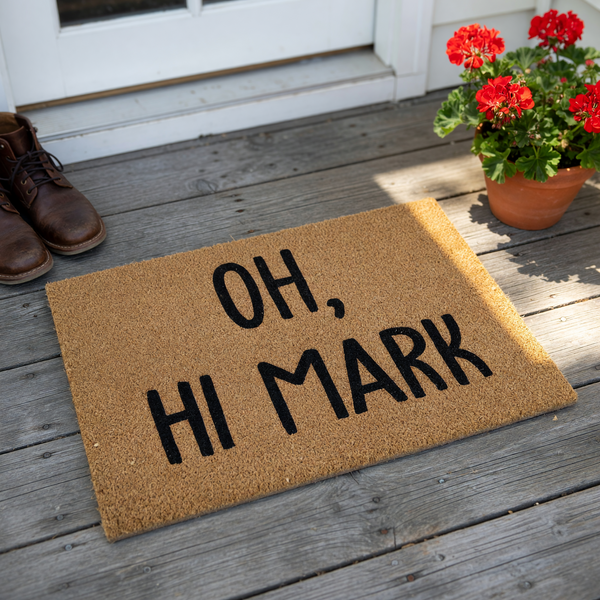 Oh Hi Mark funny doormat made of natural coir fiber with a textured brown surface, featuring bold black lettering that references a classic movie quote to welcome guests to your home with a humorous and unique front porch decor