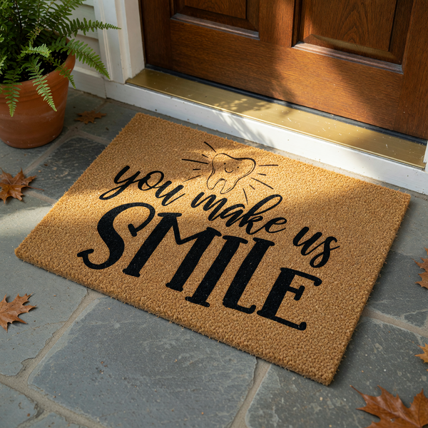 You Make Us Smile Dentist Doormat featuring a cute illustrated tooth icon with radiating lines, printed in bold black lettering on a natural tan coir fiber mat against a clean white background for a welcoming dental office