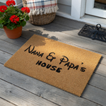 Nana and Papa's House coir doormat featuring a natural tan fiber texture and bold black lettering in a whimsical font, creating a welcoming entrance piece for a grandparent's home on a clean white background.