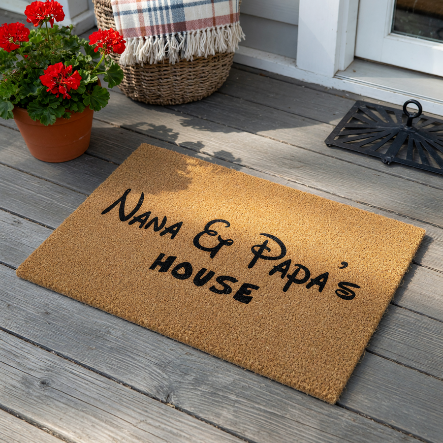 Nana and Papa's House coir doormat featuring a natural tan fiber texture and bold black lettering in a whimsical font, creating a welcoming entrance piece for a grandparent's home on a clean white background.