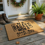 Funny Badass Doormat featuring bold black typography on a natural coir fiber background, displaying the humorous quote Be a Badass with a good ass in a mix of modern block and script fonts for a stylish and welcoming home