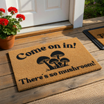 Mushroom themed coir doormat featuring a playful pun that reads Come on in! There is so mushroom! in bold black lettering, set against a natural tan fiber background for a fun and welcoming entryway decor piece for your home