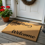 Reversible Welcome and Goodbye coir doormat featuring a natural tan fiber texture with bold black script lettering, designed to greet guests at the front door and offer a friendly farewell as they leave your home on a clean white