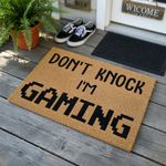 Don't Knock I'm Gaming coir doormat featuring bold, pixelated black text on a natural tan fiber background, making it a fun and functional entryway accessory for any video game enthusiast's home or bedroom door.