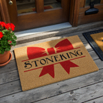 Personalized family name coir doormat featuring a large red bow graphic and a split-letter design for a custom last name, presented on a natural tan textured coir background for a festive and welcoming front porch entryway decor