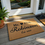 Personalized Mr. and Mrs. coir doormat featuring a black heart icon, a custom family name, and an established year, presented on a clean white background for a classic wedding or housewarming entrance decor style.