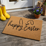 Happy Easter coir doormat featuring a natural brown fiber texture and black script lettering that incorporates stylized bunny ears into the design, creating a festive spring entryway decor piece for your front porch.