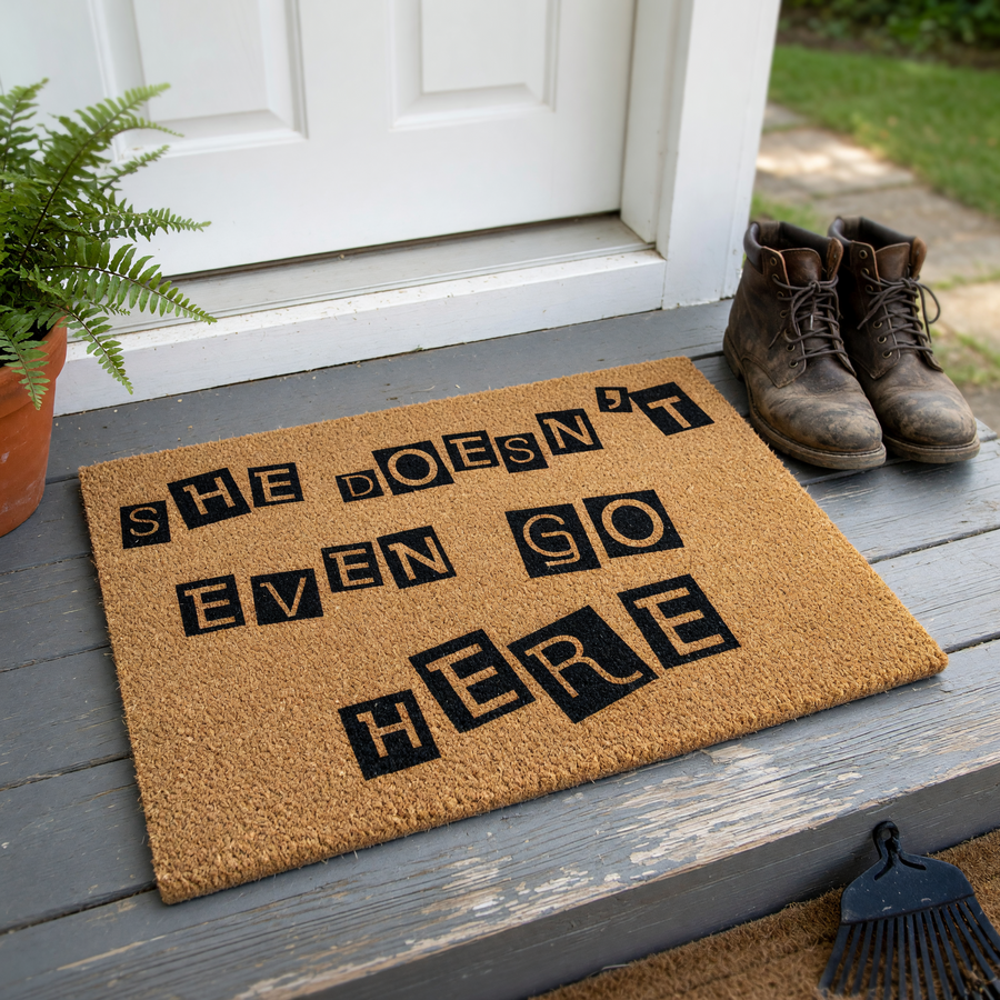 She Doesn't Even Go Here coir doormat featuring a funny movie quote printed in a ransom note style with black letters on a natural brown coconut fiber background, perfect for a pop culture themed front porch entryway decor.